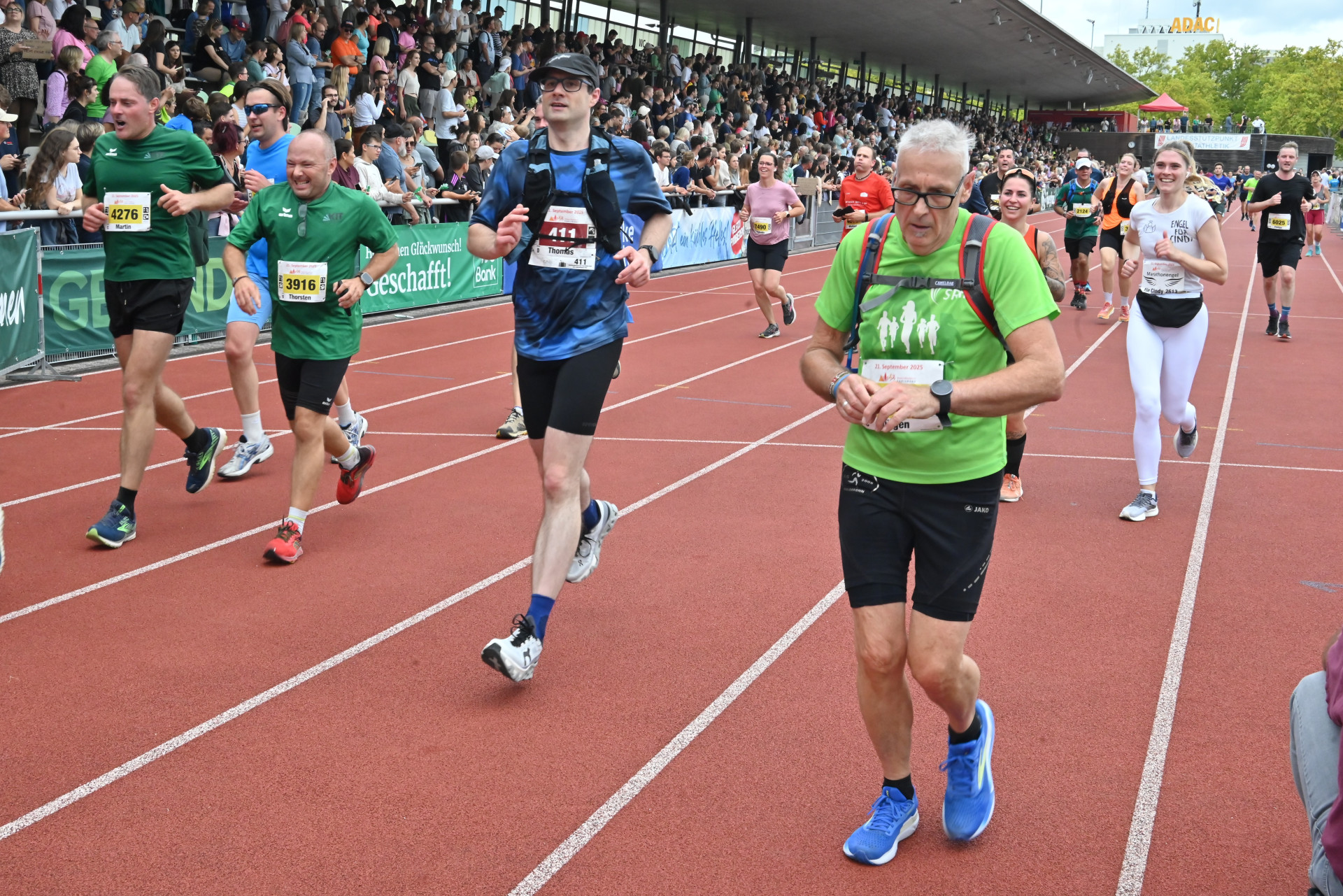 Mehrere L&auml;ufer auf der Zielgerade im Stadion. Im Hintergrund sind Zuschauer auf der Trib&uuml;ne zu sehen.